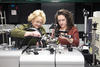 Angie Hight Walker and Amber McCreary stand side by side in the lab adjusting a complex scientific device.