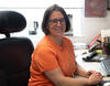 Susana Deustua sitting at her desk, smiling at the camera 