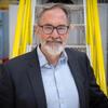 Ron Jones poses for a head shot on a yellow metal stairway