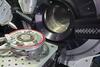 Scientific device has a circular opening; a circular metal "wafer" sits outside it on a platform. 