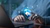 Illustration shows cloud, cybersecurity and identity icons floating over an open laptop with a person's hands at the keyboard.