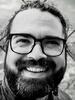 Black and white photo shows a closeup of a bearded, smiling man.