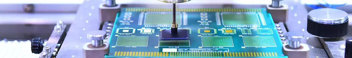 A semiconductor chip is held in a metal frame while a device works on its surface.
