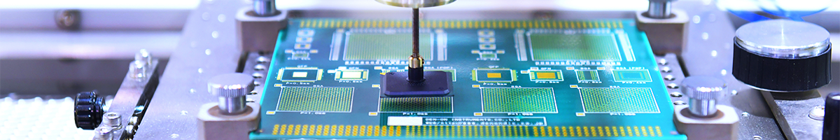 A semiconductor chip is held in a metal frame while a device works on its surface.